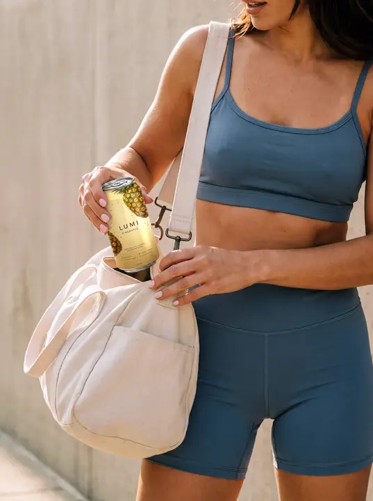 Can Mockup with an Athletic Woman Putting It into a Gym Bag